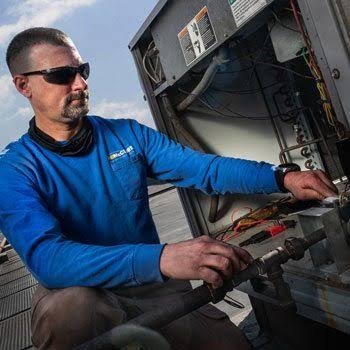 Technician checking HVAC gauges on a rooftop unit